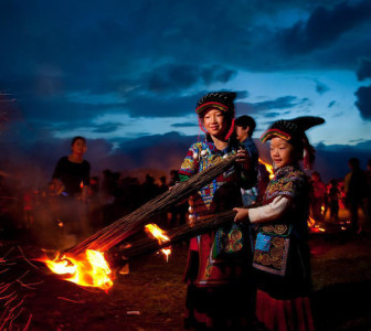 Yi people in traditional dress lighting torches