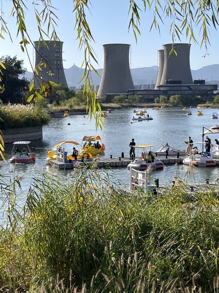 Recreational paddle-boaters play below decommissioned cooling towers at Shougang Park, Beijing.