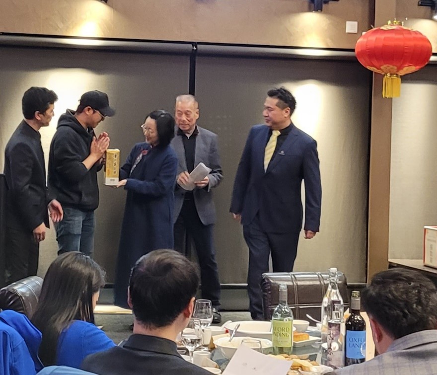 A happy auction goer being presented their won bottle of Maotai wine.